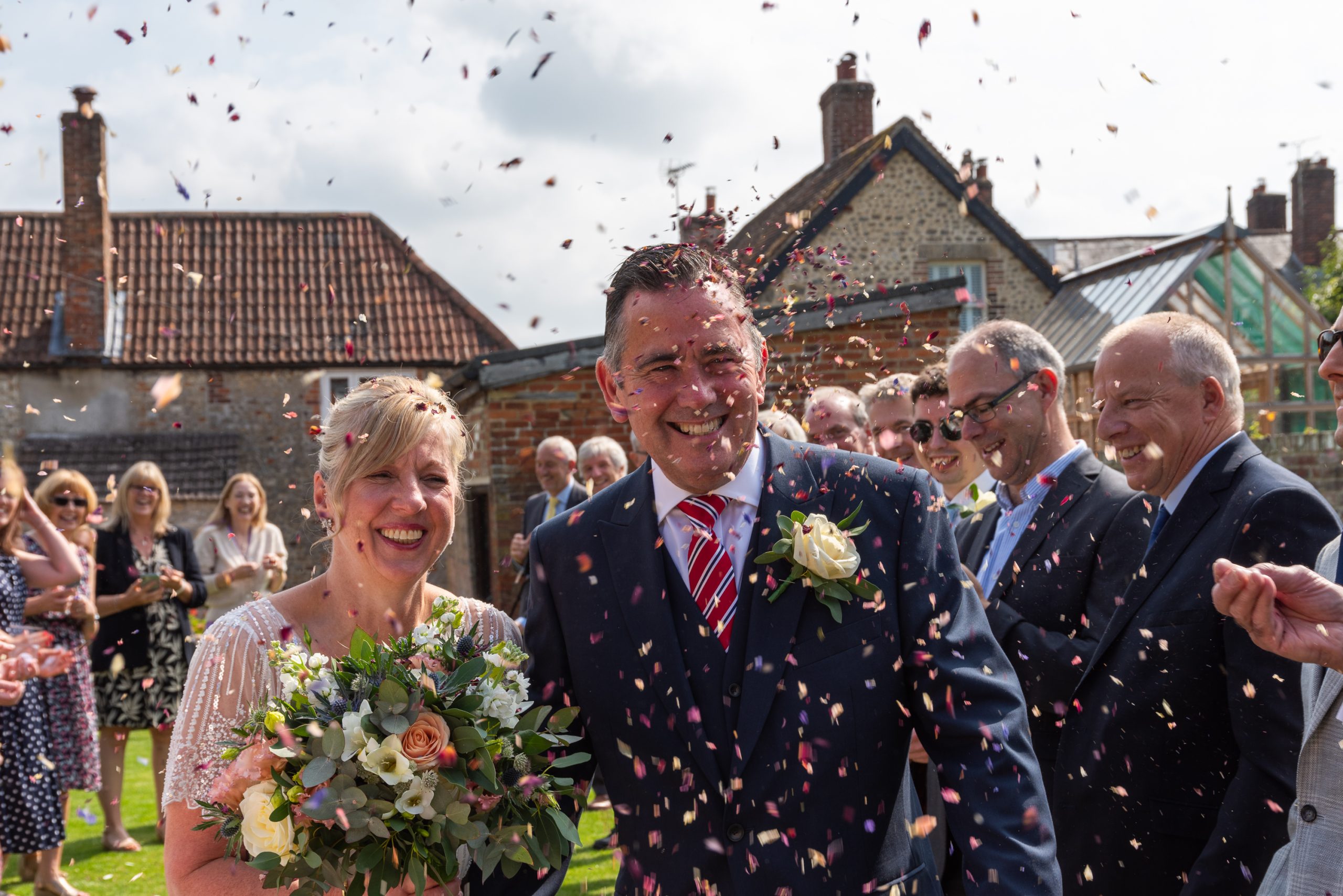 Hannah Clegg Photography capture the bride and groom walking through confetti in Warminster