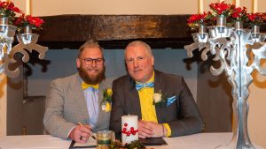 Grooms smiling together signing the register at The Great House Hotel Laleston Bridgend