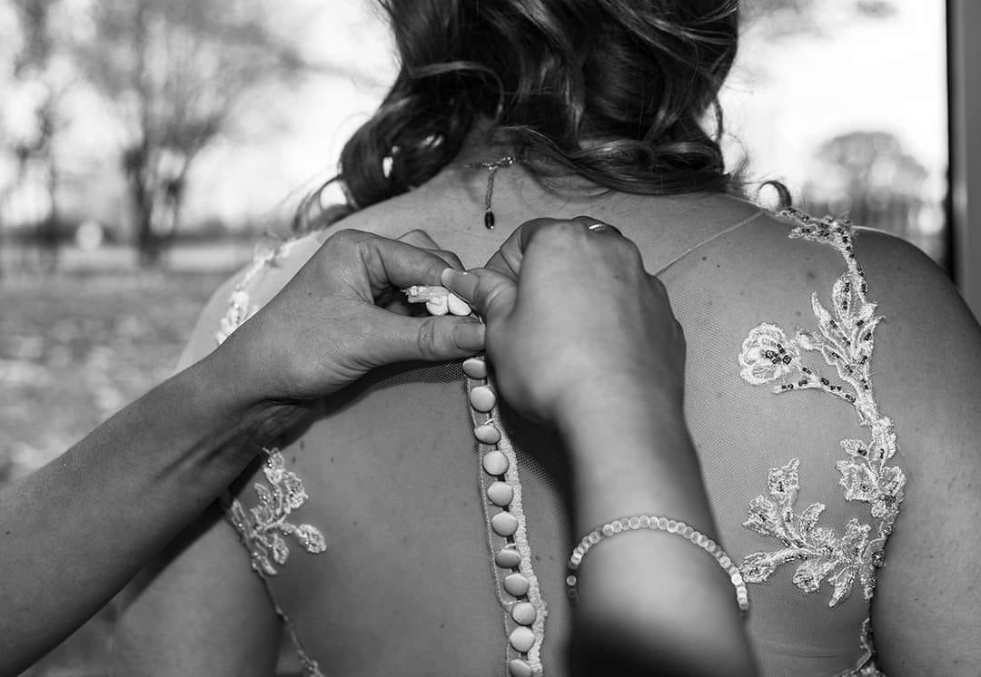 Fastening up the wedding dress during bridal prep, Hannah Clegg Photography
